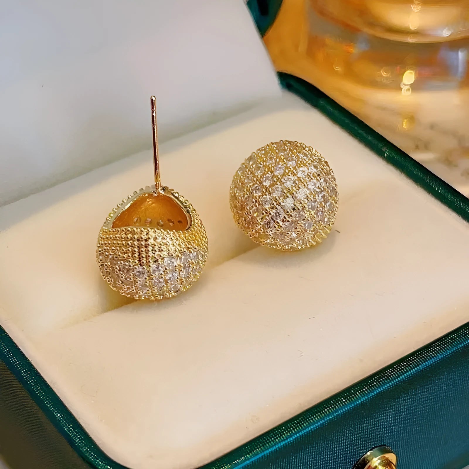 Drop-shaped geometric sphere earrings with full diamond design and little golden beans details in gold colour