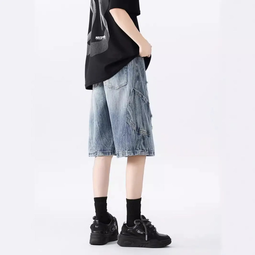 Man's washed blue denim shorts with ripped details and a loose, retro fit.