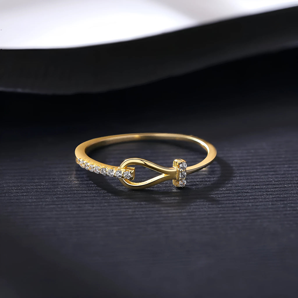 Gold electroplated silver bow ring with inlaid zirconium for women on plain background