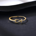 Gold electroplated silver bow ring with inlaid zirconium for women on plain background