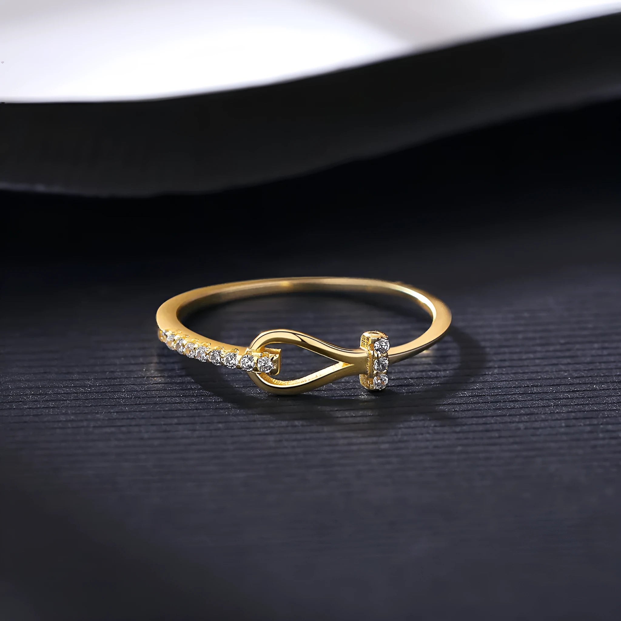 Gold electroplated silver bow ring with inlaid zirconium for women on plain background