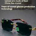 A pair of dark green frameless crystal sunglasses presented with a matching glasses case and a lens cloth.