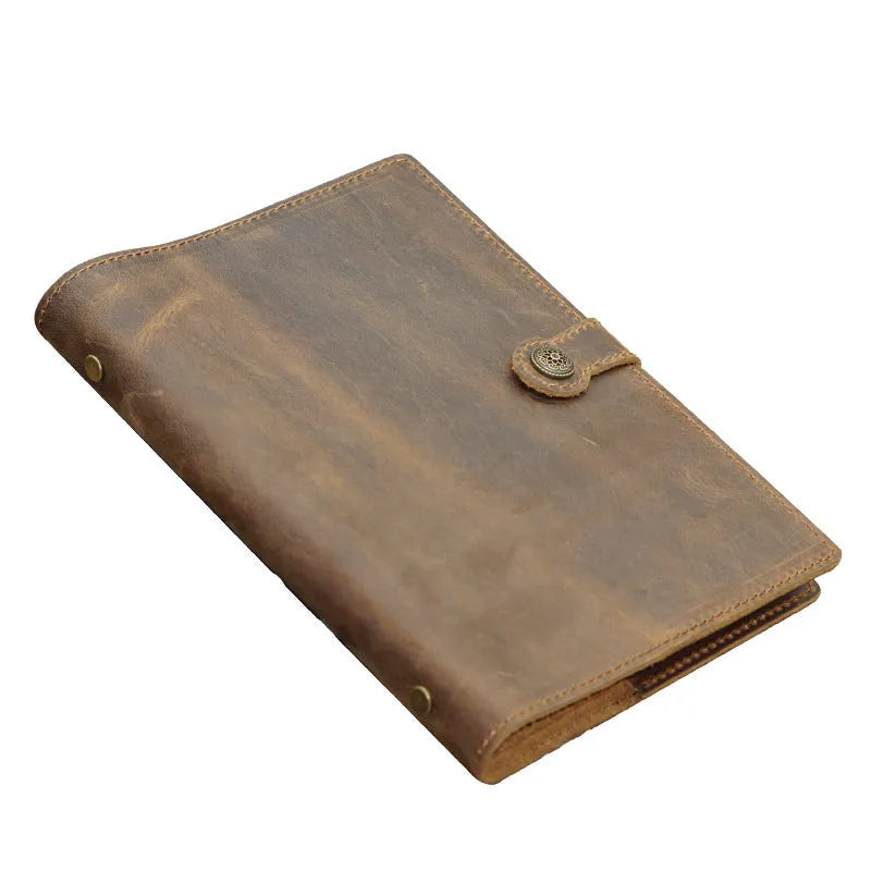 A5 handmade cowhide leather loose-leaf notebook in black with 100 sheets of kraft paper on a desk