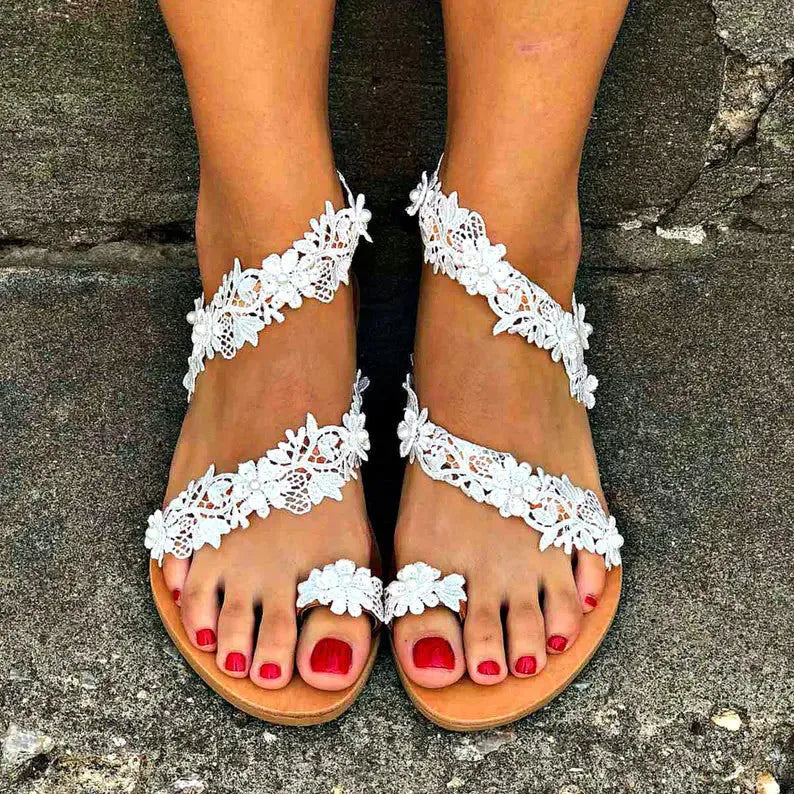 White women's flat sandals with rhinestone flower decoration on the upper.
