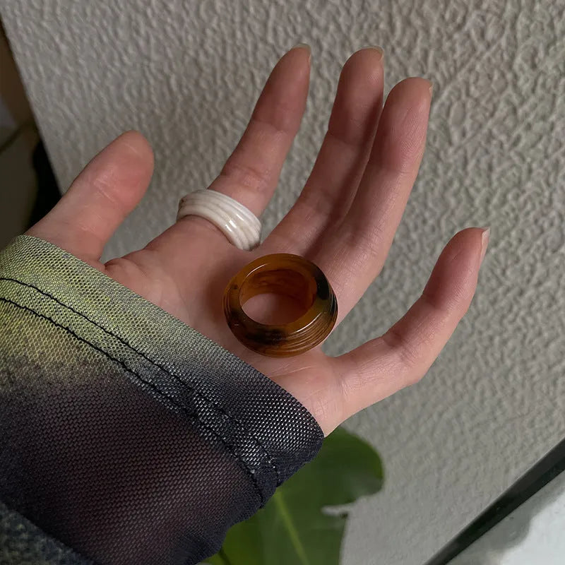 Chinese style irregular wide geometric resin ring in brown or white on display.