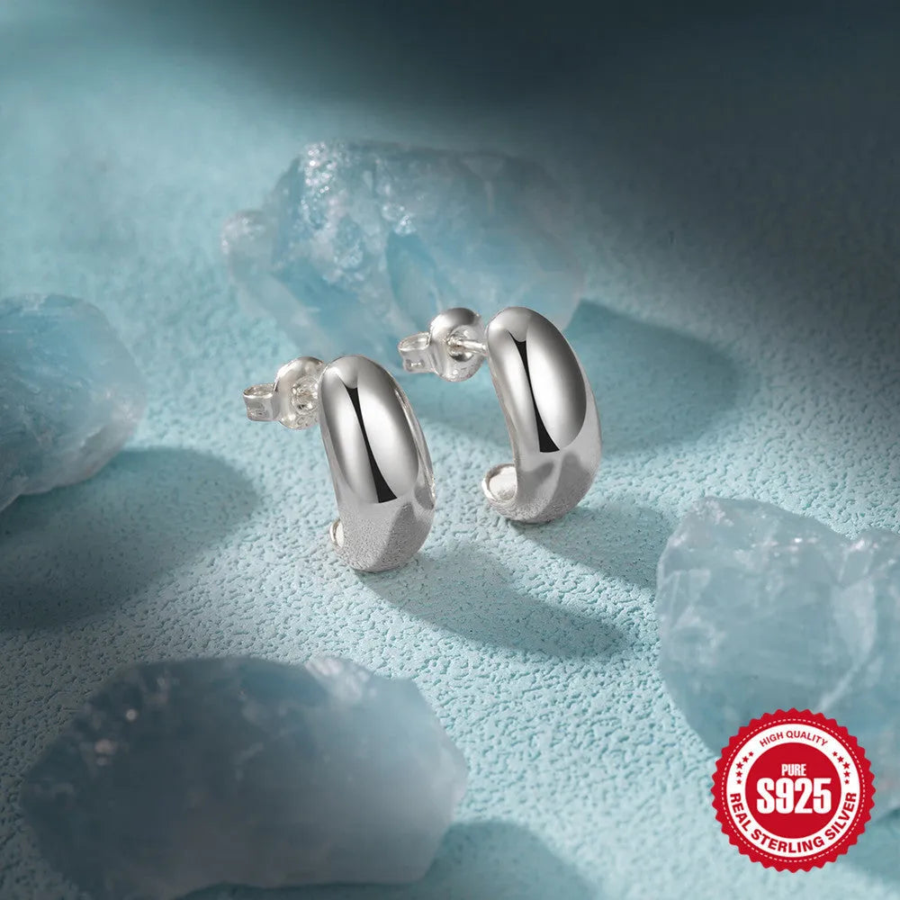 A single glossy C-shaped sterling silver stud earring on a plain background, showing gold and silver finish options.