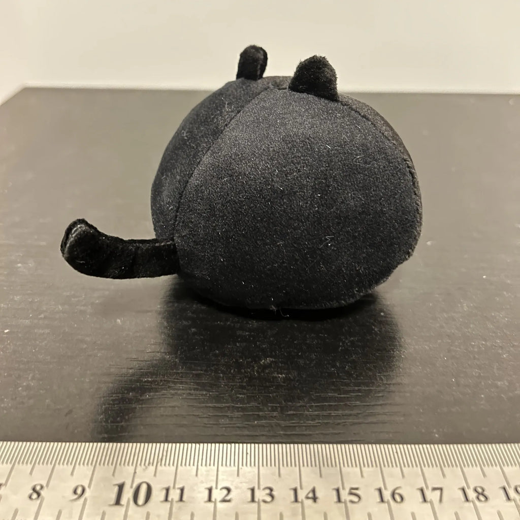 Fluffy black cat plush toy with embroidered face on a soft cushion