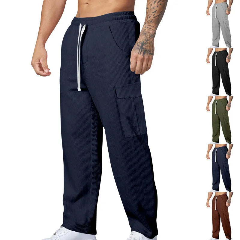Man wearing navy blue loose-fitting corduroy cargo trousers with a drawstring waist and straight wide legs.