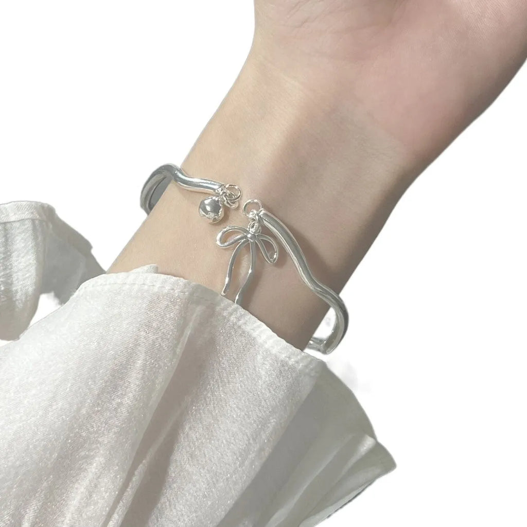 Silver adjustable women's bracelet with a bow bell charm on a zinc alloy bangle.