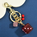 Square metal keychain pendant with cherry two-tone dice pattern and electroplated finish