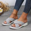 Black women's wedge slipper with a cross strap and open peep-toe on a thick rubber sole.
