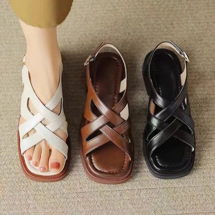 Glossy black patent leather women's sandals with a square toe and ankle strap on a flat rubber sole.