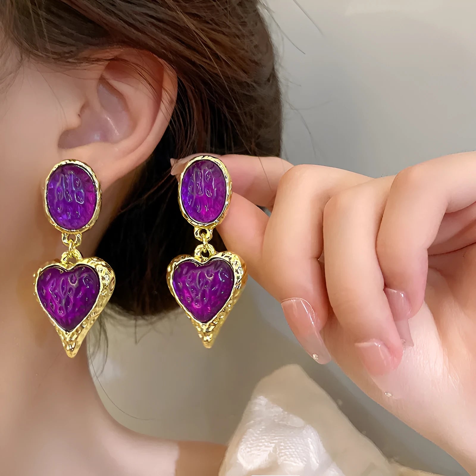 A pair of oval-shaped love heart stud earrings with a pleated surface, shown in one of four colour options.