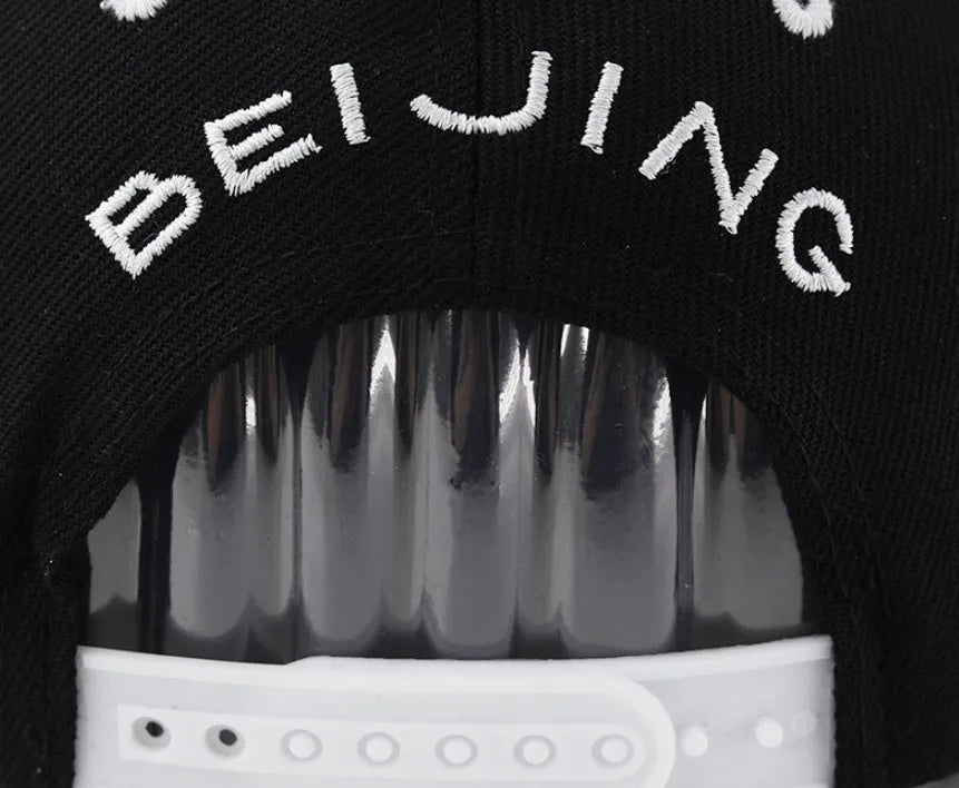 Cotton baseball hat with front letter embroidery in black colour, showing adjustable strap and dome crown.