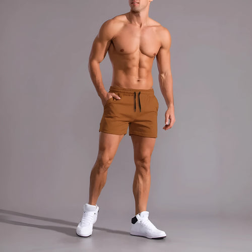 Three pairs of solid colour men's drawstring shorts in black, khaki, and light brown laid flat.