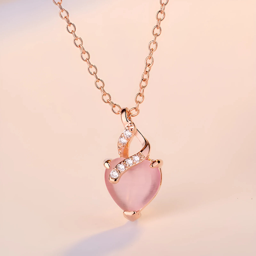 Women's pink heart crystal pendant necklace with rose gold cross chain on copper.