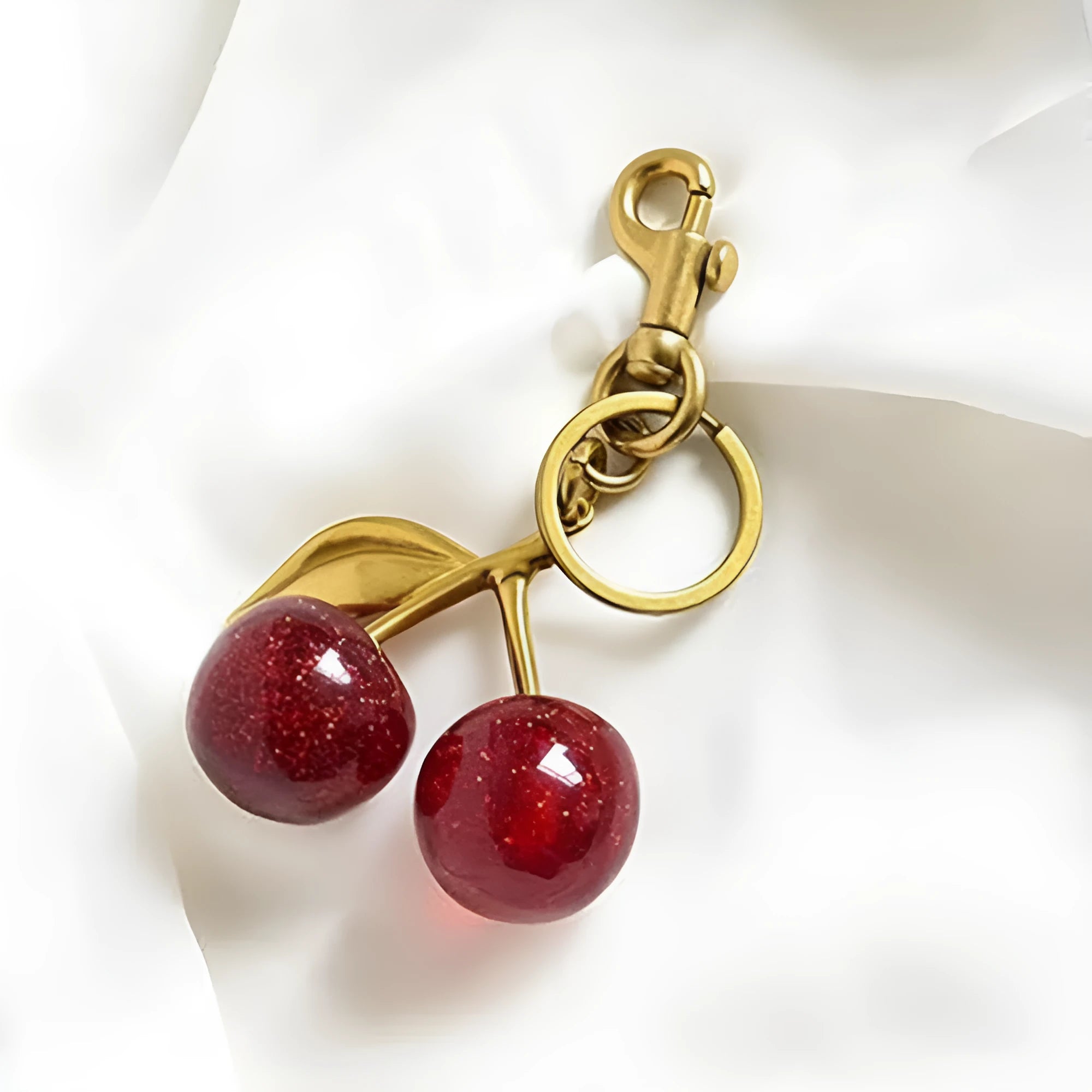 Close-up of a red zinc alloy cherry-shaped pendant key ring on a metal loop.