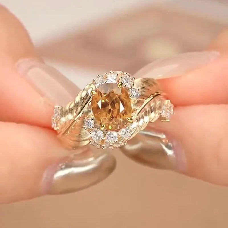 Gold-coloured copper ring with embossed feather pattern and a yellow zircon stone.
