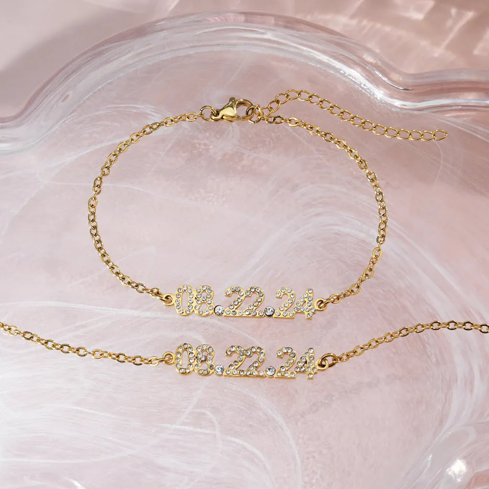 Stainless steel bracelet or necklace with diamond accents around digital numerals in gold, rose gold, or steel colour.