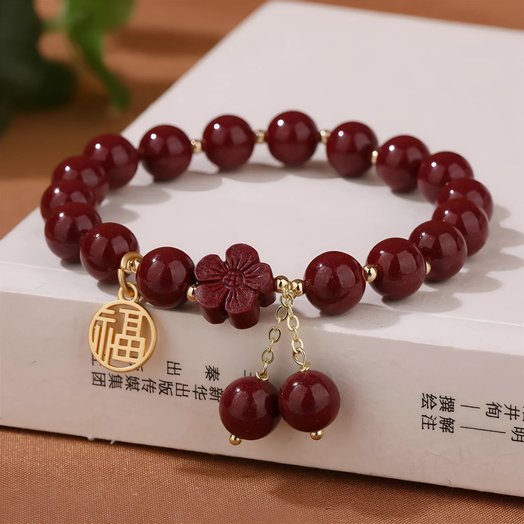 Women's handmade cinnabar bracelet with fu character charm and tassel detail in purple gold sand finish